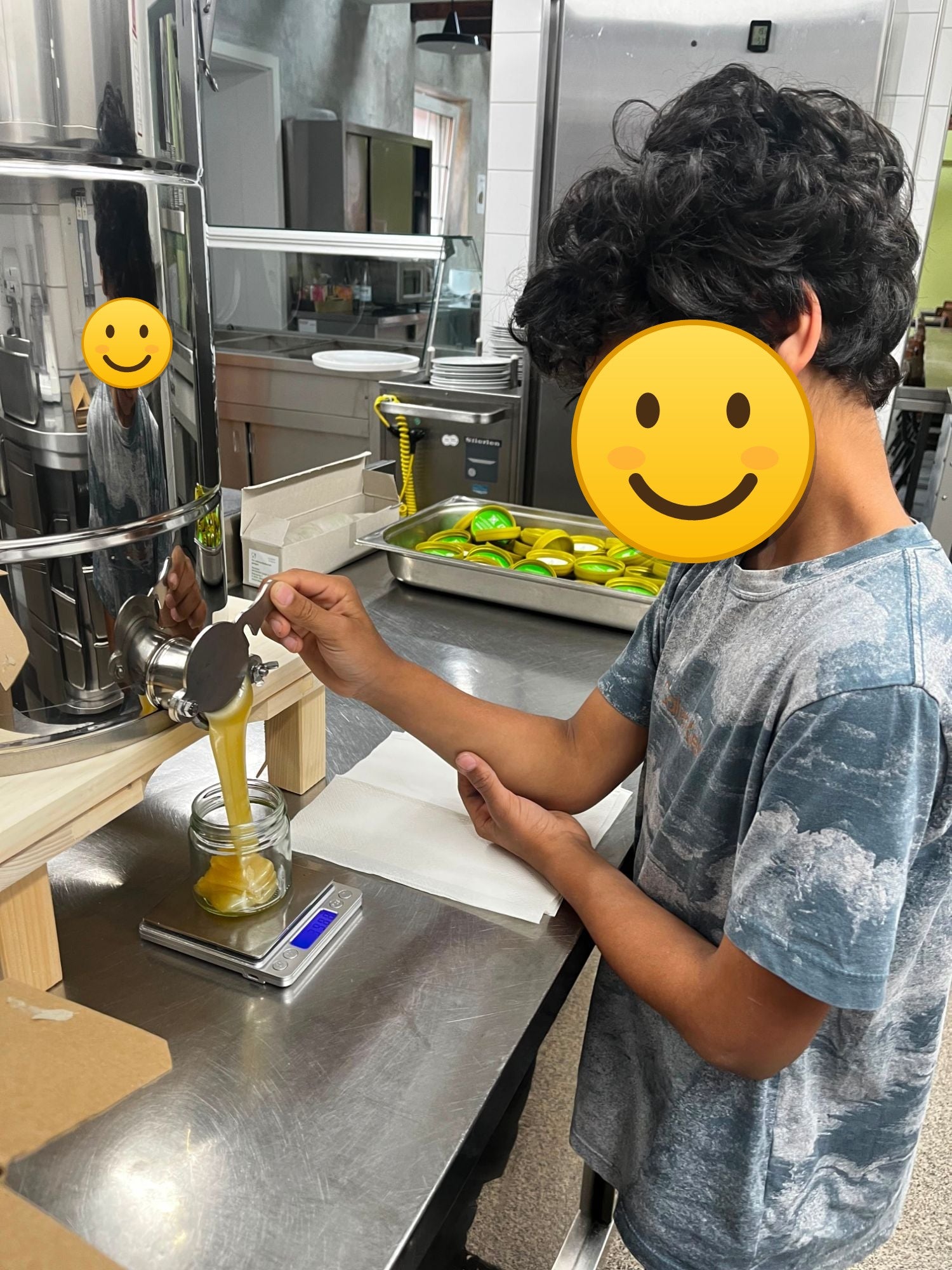 Ein Kind füllt beim Tafelprojekt Honig in ein Glas